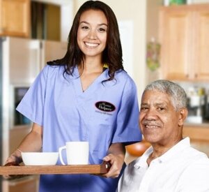 Home Helpers 24-hour caregiver holding a breakfast try for senior man